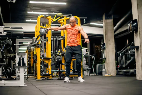 Spor salonundaki adam kettlebell ile salıncak egzersizi yapıyor.