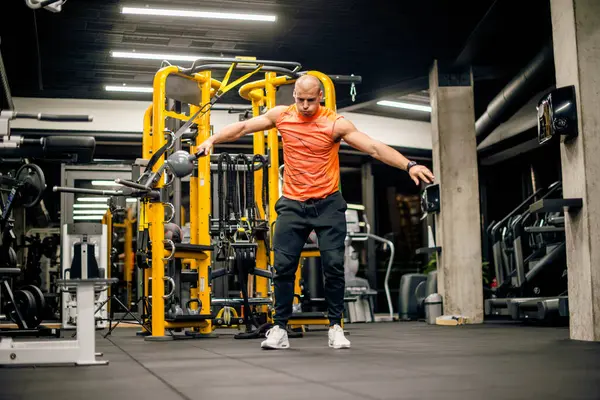 Spor salonundaki adam kettlebell ile salıncak egzersizi yapıyor.
