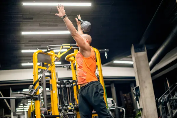 Spor salonundaki adam kettlebell ile salıncak egzersizi yapıyor.