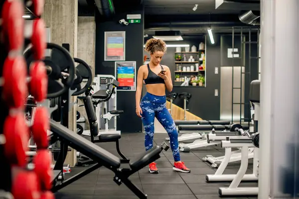 Kız beden eğitimi sırasında telefonunu kontrol ediyor.