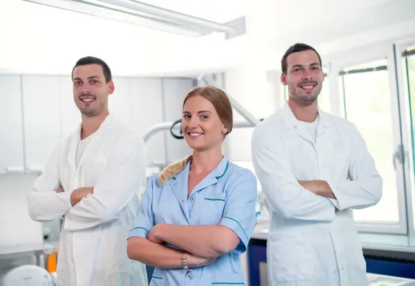 Diş hekimleri gülümseyen ayakta silah ile geçti.