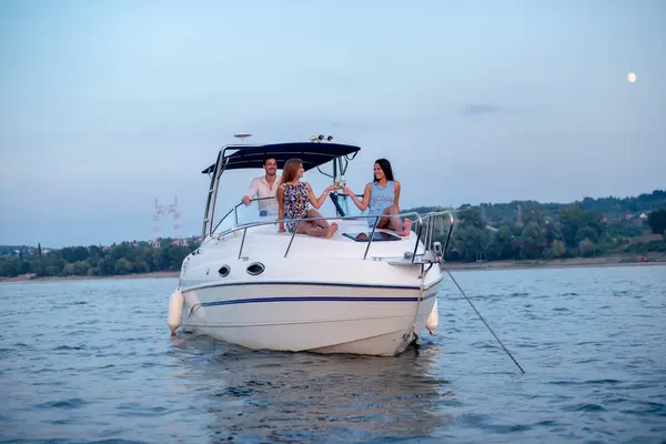 İki kız ve bir adam bir teknede eğleniyor, dinleniyorlar.