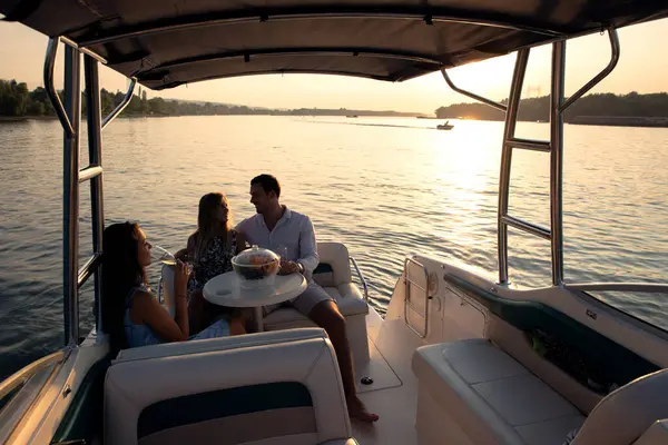Bir genç adam ve iki güzel kadın teknede eğleniyor, yaz günbatımında parti veriyorlar.