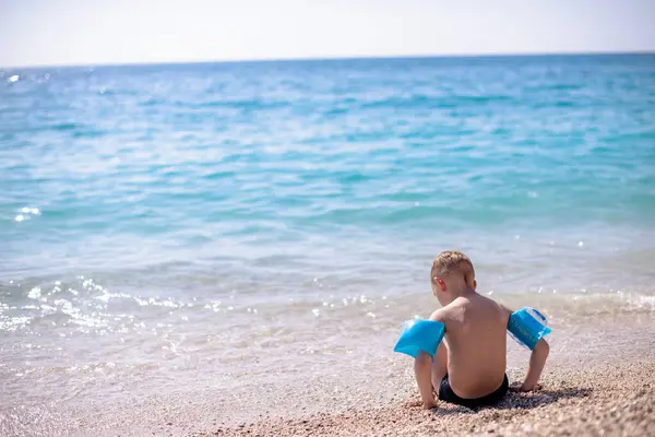 Bir çocuk güzel, çakıllı plajda oynuyor.