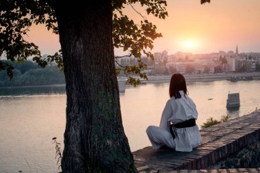 Tuğla duvarın kenarında, nehrin önünde meditasyon yapan bir kız..