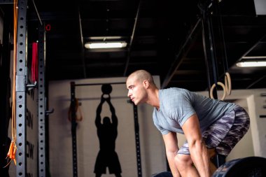 Çekici adam spor salonunda ağırlık kaldırmaya hazırlanıyor.