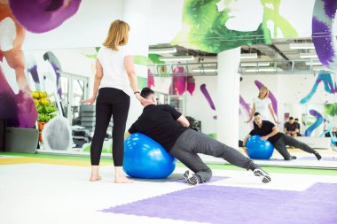 Koç son sınıftaki kadına topla egzersiz gösteriyor.