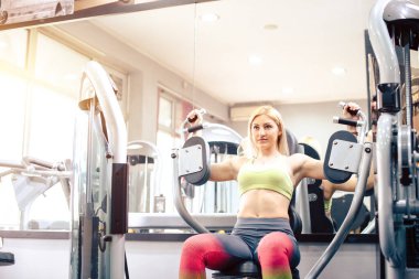 Güzel sarışın kız spor salonunda egzersiz yapıyor.