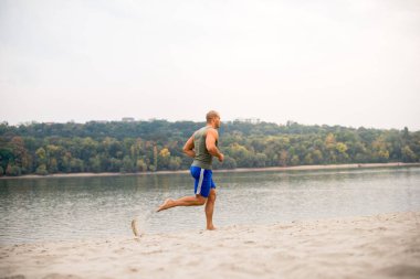 Sahilde, nehirde ve bitkilerde koşan yakışıklı genç bir atlet..