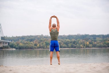 Kumsalda gerinen bir sporcu, elleri yukarıda..
