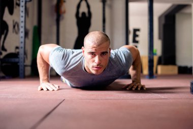 Adam spor salonunda yerde egzersiz yapıyor.