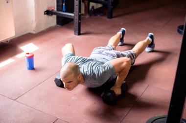 Spor salonunda ağırlık kaldıran bir adam.