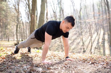 Erkek doğada egzersiz yapar, şınav çeker.
