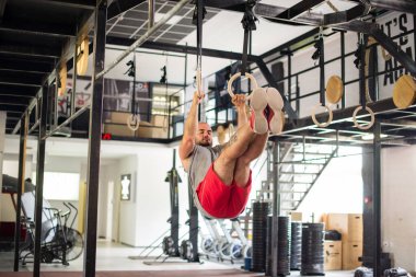 Adam spor yüzükleri üzerinde karın egzersizi yapıyor.