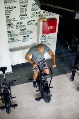 Adam spor salonunda bisikletle egzersiz yapıyor.