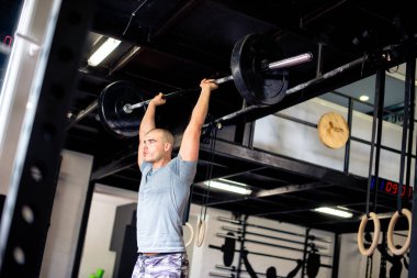 Adam spor salonunda ağırlıkları kafasının üzerine kaldırıyor.