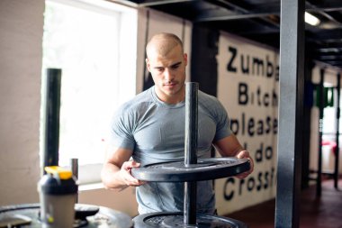 Adam beden eğitimi için ağırlık hazırlıyor.