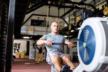 Kaslı adam spor salonunda çalışıyor.