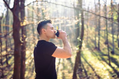 Parkta sıkı bir koşudan sonra vücudunu dolduruyor.