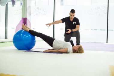 Son sınıftaki bayan spor salonunda antrenörle top antrenmanı yapıyor.