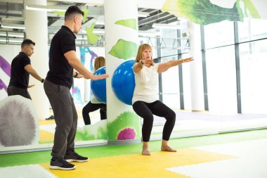 Son sınıftaki bayan spor salonunda koçuyla egzersiz yapıyor.