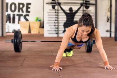 Spor salonunda şınav çeken güçlü bir kadın.