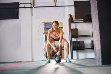 Kettlebell 'li güçlü genç bir kadın spor salonunda çalışıyor.