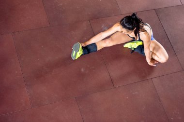 Kız spor salonunun zemininde egzersiz yaptıktan sonra esniyor.