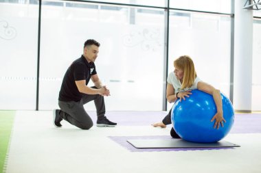 Antrenör iyi egzersiz için müşterisini kontrol ediyor.