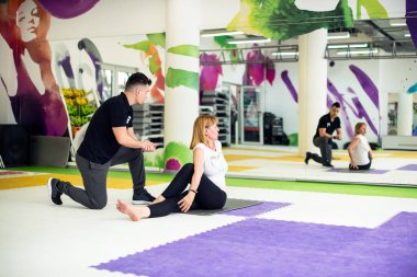 Spor salonunda koçla egzersiz yapan bir kadın.