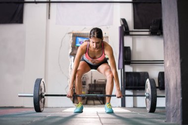 Genç kız spor salonunda ağırlık kaldırıyor.