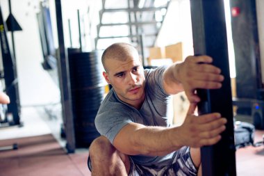 Genç adam spor salonunda geriniyor.