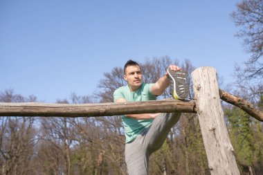 Genç adam doğadaki egzersizden sonra geriniyor.