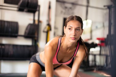 Spor salonundaki genç kadın, egzersiz yapıyor.