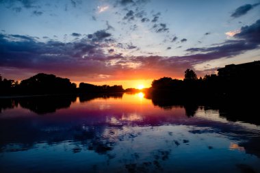 Göl suyunda bulutlu güzel günbatımının yansıması. Romantik bir yer.