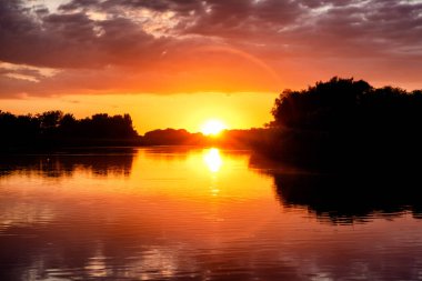 Göl suyunda bulutlu güzel günbatımının yansıması. Romantik bir yer.