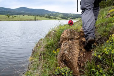 Balıkçılar elinde oltayla nehir kenarında yürüyorlar.