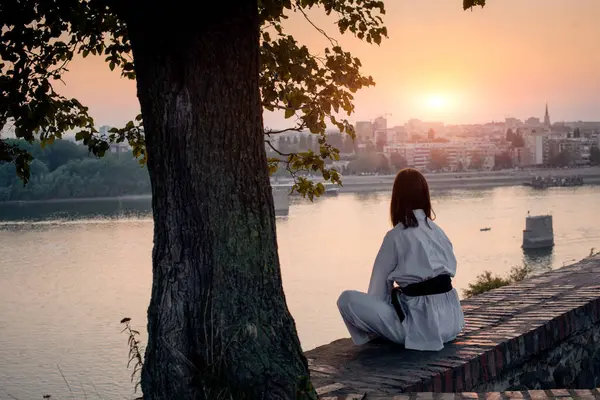 Tuğla duvarın kenarında, nehrin önünde meditasyon yapan bir kız..