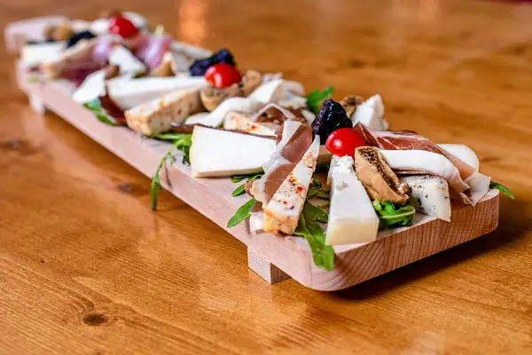 Ahşap masada peynir ve jambonla güzel dekore edilmiş yemek servisi. Gıda dekorasyonu