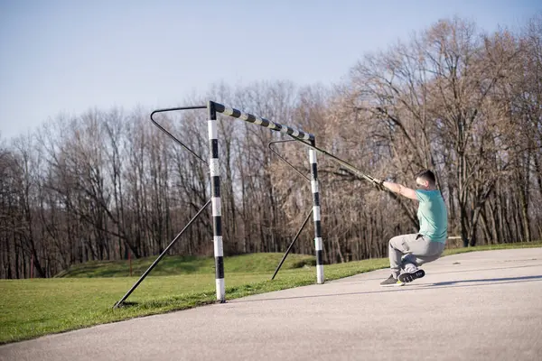 Doğada süspansiyonlarla egzersiz yapan adam