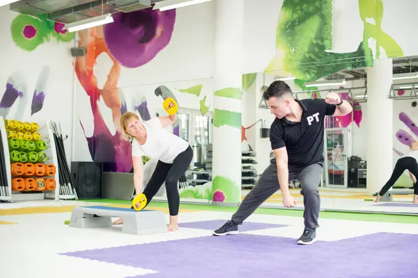 Kıdemli kadın antrenman yapıyor, koçunun yardımıyla.