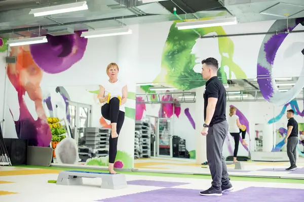 Kıdemli kadın spor salonunda kişisel antrenörüyle çalışıyor.