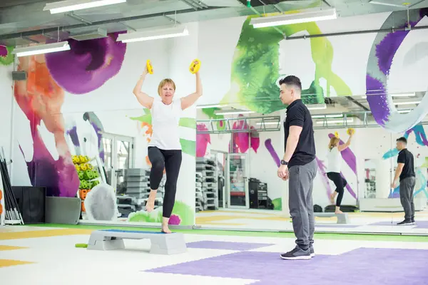 Kıdemli kadın antrenörüyle beden eğitimi yapıyor.