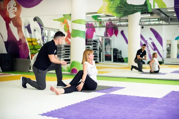 Spor salonunda koçla egzersiz yapan bir kadın.