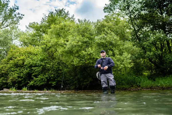 Erkekler oltayı tutuyor ve suyun içinde duruyorlar.