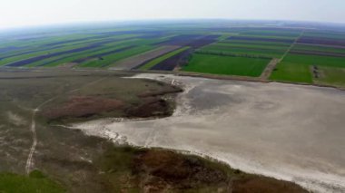 Doğada yaz mevsiminde tarlaların ve büyük göllerin havadan çekilmiş videosu Slano Kopovo 'yu saklar