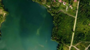 İnsansız hava aracı turkuaz gölü kıyısındaki evler ve ağaçların üzerinden uçuyor. Saransko jezero