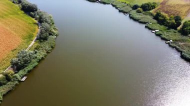 Hava aracı, güneşli bir günde yeşil bitki örtüsüyle çevrili akan nehri takip ediyor.