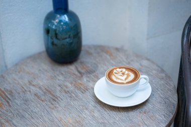 Sıcak sanat sütlü kahve. Arka plan kahve fincanı ve fasulye. Eski mutfak masasında..