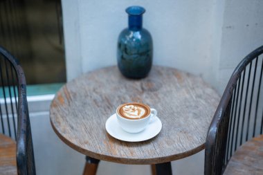 Sıcak sanat sütlü kahve. Arka plan kahve fincanı ve fasulye. Eski mutfak masasında..